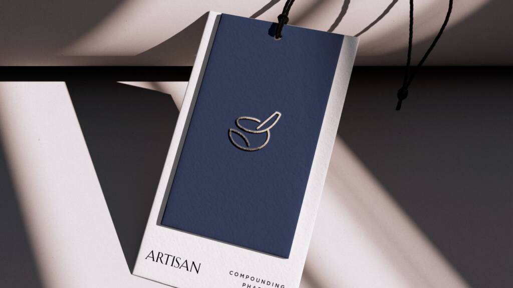 Pharmacy tag design featuring a custom mortar and pestle logo design on a navy blue hang tag, showcasing elegant compounding pharmacy branding.