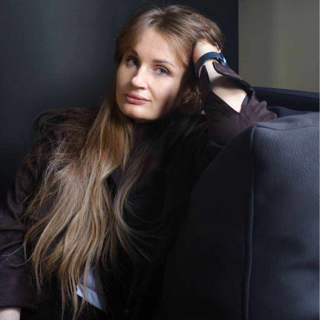 Portrait of Inna Havryk, founder of Havry Design, sitting on a sofa and looking at the camera.
